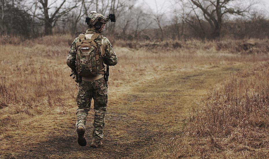 Soldier walking down a grassy dirt road